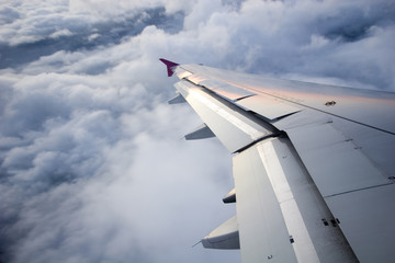 Wschód słońca odbijał się na skrzydle samolotu, wysoko na niebie, nad chmurami