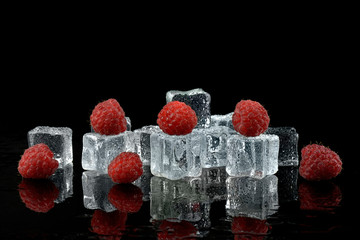 Maliny z kostkami lodu na czarnym tle