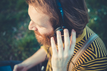 young bearded stylish handsome hipster man listening music