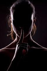 nieznana kobieta z twarzą w cieniu trzymając palec na ustach