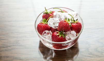 Fresh strawberries with ice cubes in the glass bowl