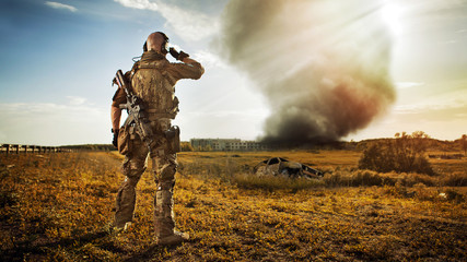 Żołnierz z karabinem patrzy na dym pod miastem. R