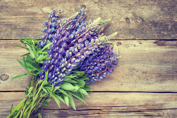 Bunch of blue lupine flowers on wooden background. Retro styled