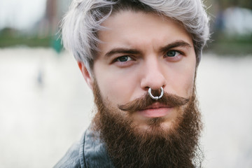 Bearded hipster with nose ring in leather jacket