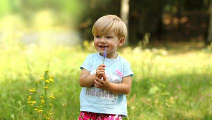 Mała dziewczynka z kwiatkiem na łące.