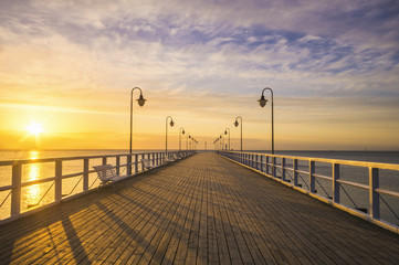 drewniane molo nad morzem oświetlone w nocy stylowymi lampami