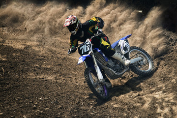 Motocross jeźdźca tworzy dużą chmurę pyłu i gruzu