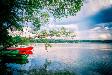 Łódka i jacht w blasku chmur i jeziora