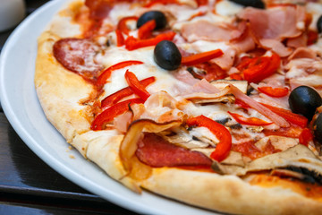 Pizza z czerwoną świeżą papryką i czarnymi oliwkami na bielu talerzu
