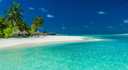 Drzewka palmowe i plażowi parasole nad laguną i białą piaskowatą plażą, Maldives