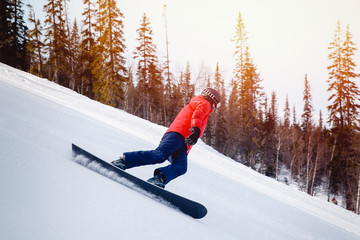 sportowiec z twardym snowboardem do slalomu na ścieżce ośrodka narciarskiego wchodzi na zakręt, region Murmańsk, Rosja. zachód słońca.