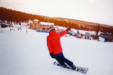 sportowiec z twardym snowboardem na slalom na ścieżce ośrodka narciarskiego wchodzi na zakręt, region Murmańsk, Rosja. zachód słońca. Koncepcja osiągnięcia celów.