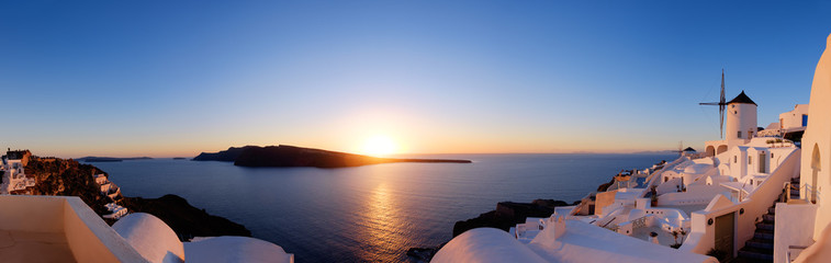 Tradycyjne apartamenty i wiatraki w wiosce Oia na zachód słońca, panoramiczny obraz