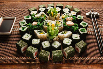 Sztuka kulinarna, tradycyjna kuchnia japońska. Okrągły ornament zestaw zielony rolek sushi serwowane na brązowy słomy mat, zbliżenie. Japońskie owoce morza, kulinarne arcydzieło.