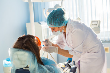 Woman dentist in the medical dental office. She is heals patient