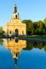Reflection in water of the historic entrance gate of the baroque Branicki Palace in setting sun, Białystok, Poland