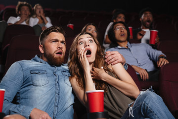 Shocked young couple watching a horror movie