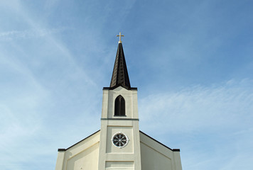 Christian background photo of a majestic church steeple with a cross and a clock tower on a blue sky background
