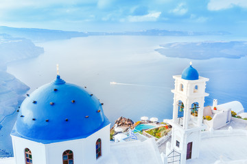 Grecja, wyspa Santorini w Morzu Egejskim. Zapierająca dech w piersiach sceneria z niebieskim domed church na pierwszym planie i epickiej panoramy wyspy w tle.
