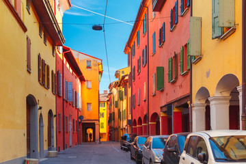 Medieval street portico with bright colored houses in the Old Town in the sunny day, Bologna, Emilia-Romagna, Italy