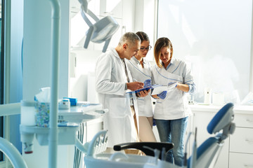 Zespół dentysty medycznego w gabinecie stomatologicznym omawia praktykę i bada listę pacjentów.