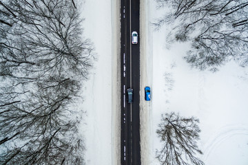 Trzy pokryte śniegiem samochody jeżdżą wzdłuż drogi. Widok z lotu ptaka. Zdjęcie z drona