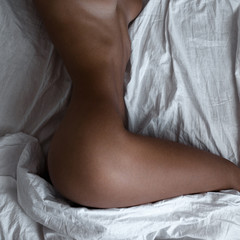 Seksowna opalona dziewczyna na białym łóżku