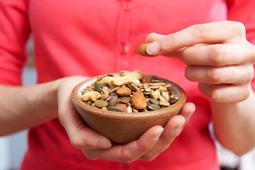 Close Up Of Woman Eating Bowl Of Healthy Nuts And Seeds