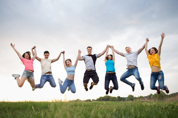 Młodzi ludzie skaczący na tle zachodu słońca nieba