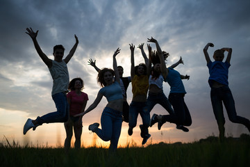Młodzi ludzie skaczący na tle zachodu słońca nieba