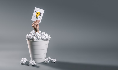 Ręka rozciąga arkusz z pomysłem ze śmietnika