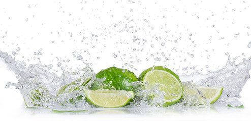 Świeże limonki z wodnym pluśnięciem nad białym tłem.