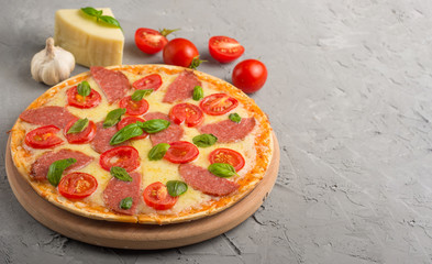 Karmowi składniki i pikantność dla kulinarnego mazarella sera, czereśniowych pomidorów, czosnku, basilu i wyśmienicie Włoskiej pizzy na popielatym betonowym tle. Copyspace. Widok z góry. transparent