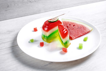 Deser arbuzowy. Panakota i galaretka w białym talerzu na tle tabeli. Widok z góry