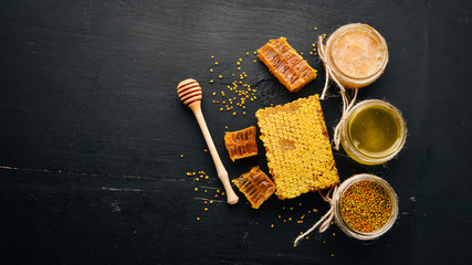 Zestaw miodu i produktów pszczelich. Miód w plastrze miodu. Na czarnym tle drewnianych. Wolne miejsce na tekst. Widok z góry.