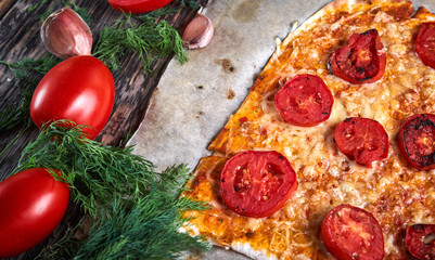 świeża gotowana pizza na papierze do pieczenia i składniki do pizzy i sosu na drewnianym stole