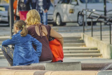 matka siedzi na schodach i chroni pociechy przed zgiełkiem wielkiego miasta