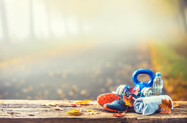 Niebieskie buty sportowe i woda ułożone na drewnianej desce.