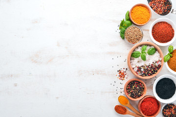 Zestaw przypraw i ziół na biały drewniany stół. Bazylia, pieprz, szafran, przyprawy. Indyjska kuchnia tradycyjna. Widok z góry. 