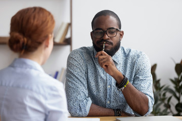 Diverse business people sitting in office, black ceo interviewing female for company position feel doubts that candidate meets requirements. Bad first impression and unsuccessful job interview concept