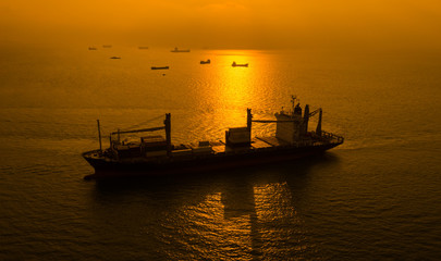 kontenery transportowe sylwetka na morzu i na tle wschodu słońca