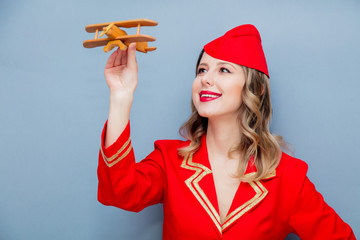 stewardessa w czerwonym mundurze z drewnianym samolotem