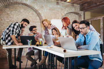 Grupa młodzi ludzie biznesu w mądrze przypadkowej odzieży pracuje wpólnie w kreatywnie biurze