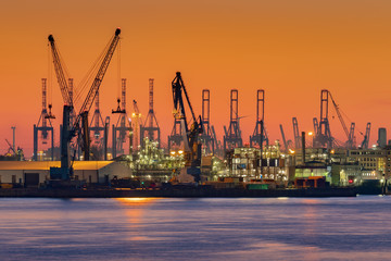 Żurawie sylwetki przed wieczornym niebie w Hamburg Harbour, Niemcy, o zmierzchu. Port w Hamburgu (Hamburger Hafen) to port morski nad rzeką Łabą. To największy port w Niemczech.