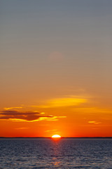 jasne pomarańczowe słońce z odbiciem w wodzie podczas zachodu słońca nad morzem