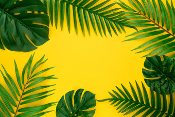 Skład lato z miejsca na kopię. Rama wykonana z zielonej tropikalnej palmy i liści Monstera na pastelowym żółtym tle. Koncepcja lato. Płaski układ, widok z góry