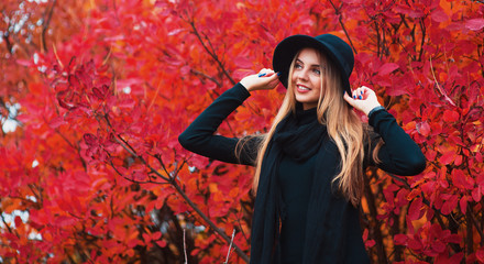 Fasonuje jesień portreta uśmiechniętej kobiety w czarnym kapeluszu na czerwonym liścia tle
