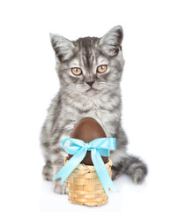 Pręgowany kotek z wielkanocnym koszyku z czekoladowym jajkiem. na białym tle