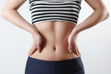 zdjęcie zbliżenie. smukła dziewczyna w sportowych leginsach i temat pokazuje ciasną sylwetkę i brzuszek, trzyma ręce na bokach talii na białym tle