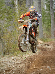 Kierowca motocrossu skacze z rowerem z dużą prędkością na torze wyścigowym.